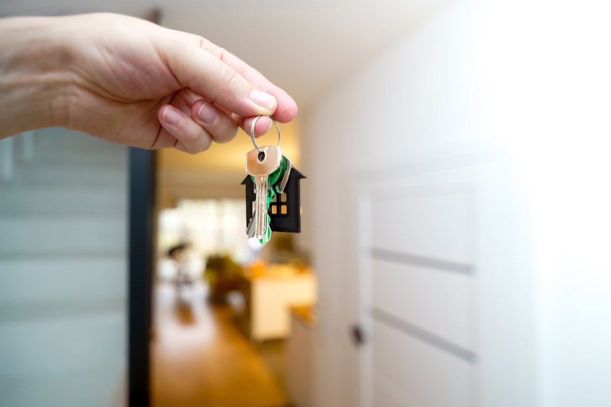 Hand holding house keys in front of a property entrance, representing real estate PPC lead generation